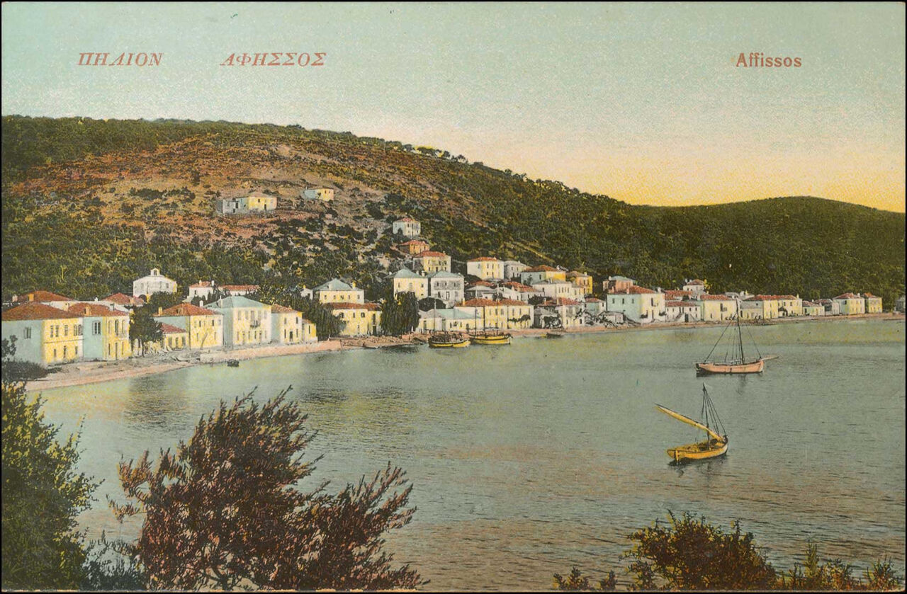 Hand-coloured postcard of Afissos around 1920: a curve of pale houses round the bay, green hills, two sailing boats